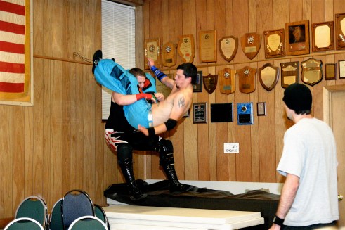 Sean Vincent power bombs Billy McNeil onto a set of tables. (Photo Credit Michael R Van Hoogstraat)